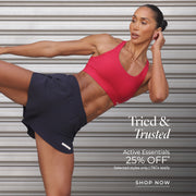 Woman in black shorts, red sports bra striking active pose. Text: Tried and trusted, Active Essentials, 25% off. Selected Styles only. T&Cs apply. Shop Now