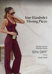 A woman stands on outdoor steps wearing a burgundy fitted tank top and matching wide-leg active pants, accessorized with sunglasses and holding a drink. Text: Your Wardrobe's Missing Piece. All Day Active Midrise Pants 30% Off* T&Cs apply - Shop Now