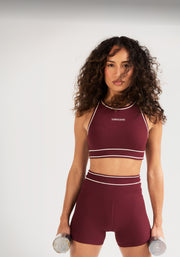 A woman wearing a burgundy sports bra and matching high-waisted shorts, holding dumbbells against a clean light background. Text: 48 Hours Only. 15% OFF New Arrivals* Shop New Arrivals