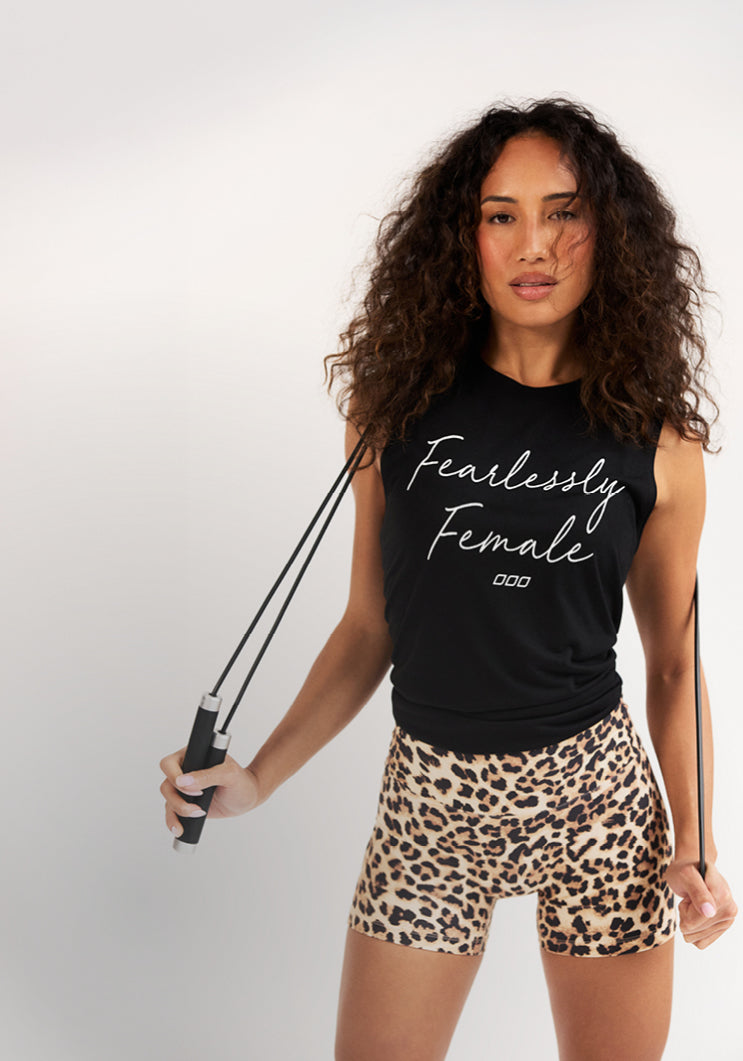 A woman with long curly brown hair holds a black skipping rope over her shoulder, wearing a black sleeveless top and leopard-print shorts against a light grey background. Text: 48 Hours Only. 15% Off* New Arrivals. Shop Now.