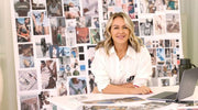 Lorna Jane Clarkson wearing a white long sleeve button up shirt, standing in front of a wall with magazine clippings