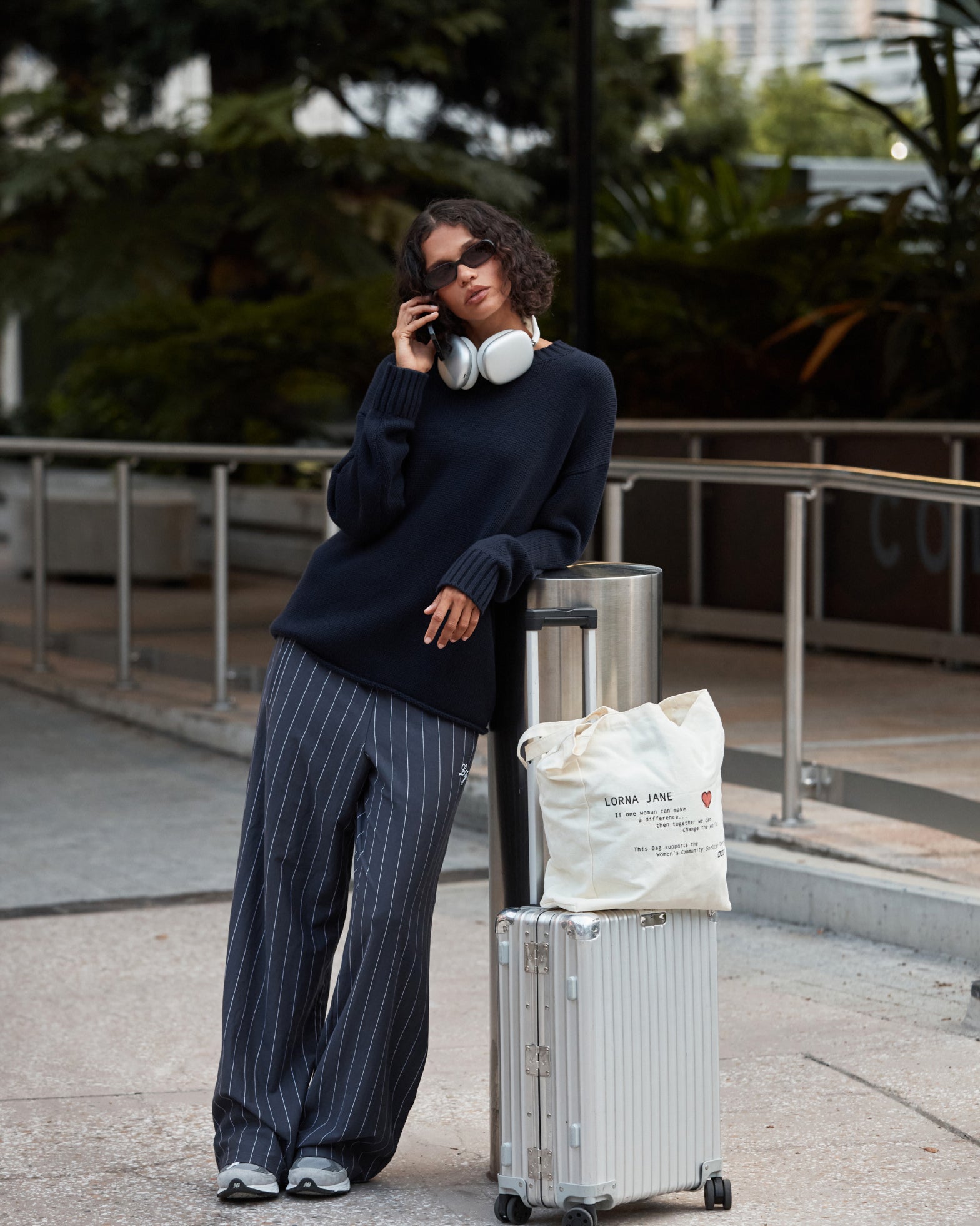 Woman wearing Lorna Jane pants and sweater, standing with her luggage