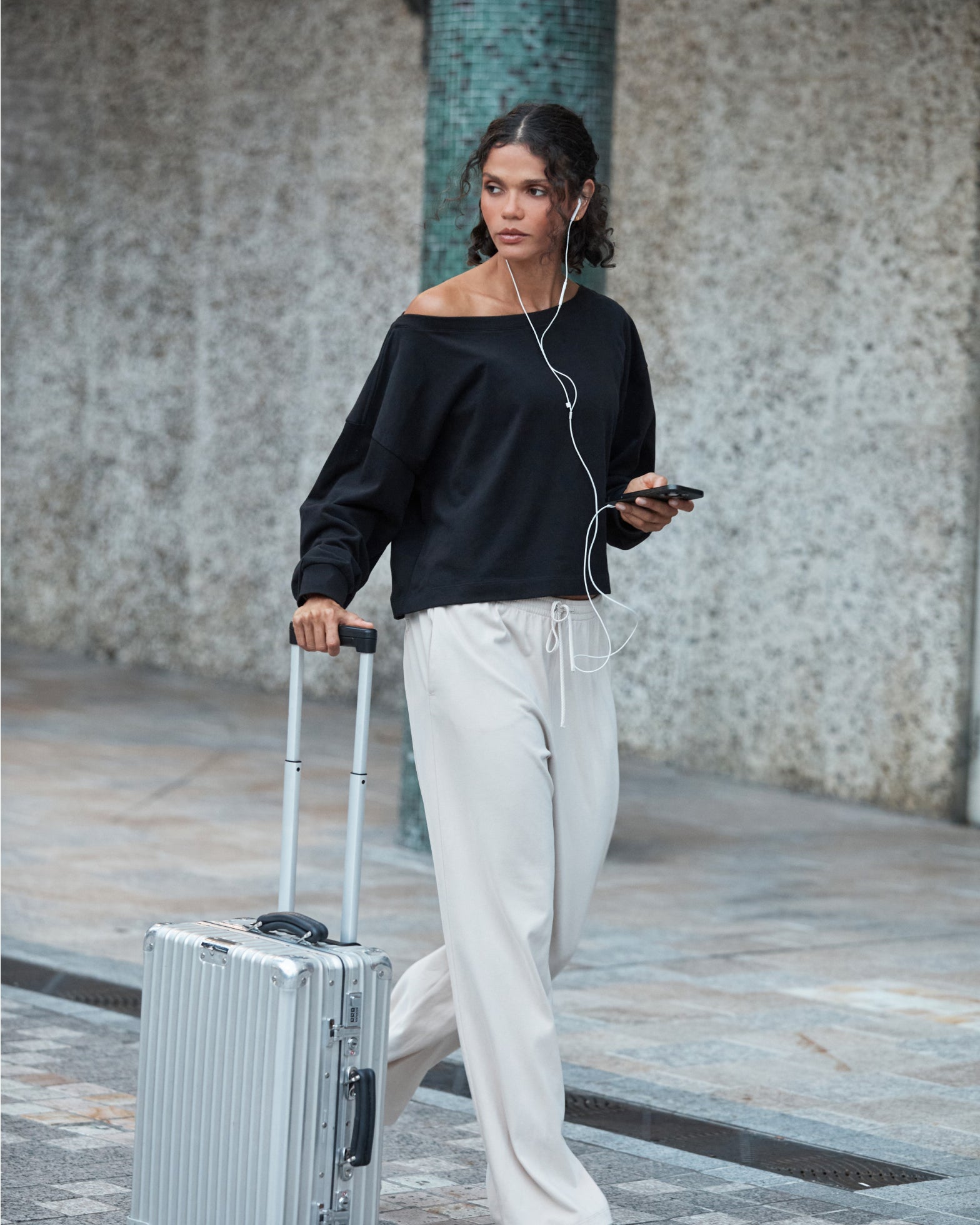 Woman wearing Lorna Jane pants and sweater, walking with her luggage