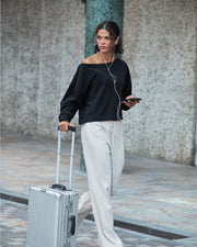 Woman wearing Lorna Jane pants and sweater, walking with her luggage