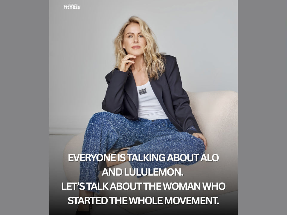 Lorna Jane sits on a cream chair wearing a navy blazer, white tank top, and blue knit pants, with bold text promoting a feature about the woman who started the activewear movement.
