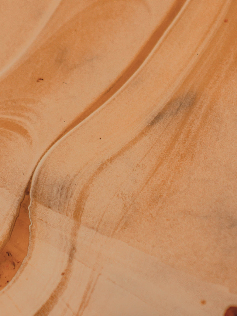 Abstract flowing sandy-toned marble pattern in warm caramel and cream swirls.