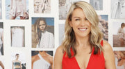 Photo of Lorna Jane Clarkson wearing a red top standing in front of a wall with photos