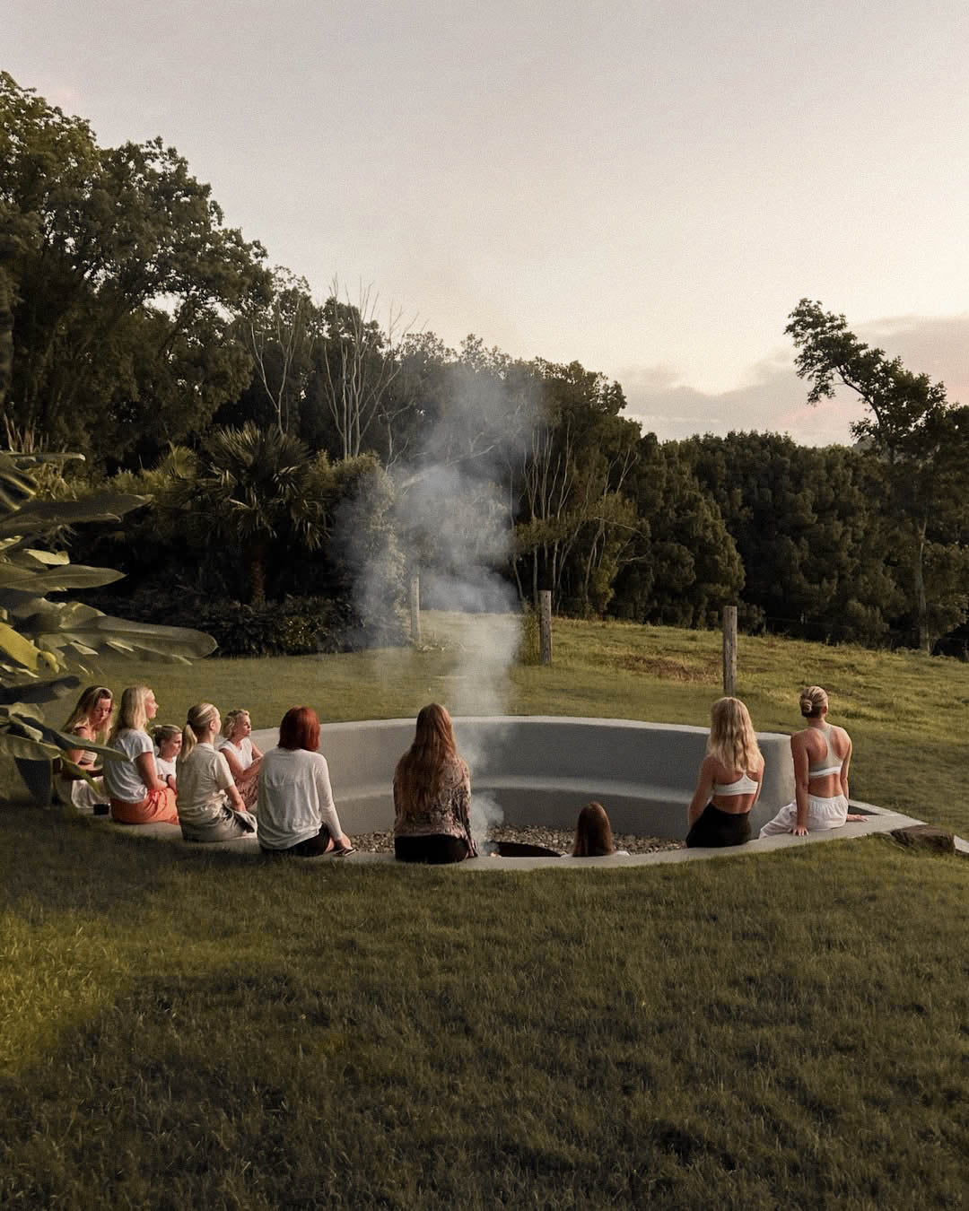 Several women sitting around a tiered firepit.