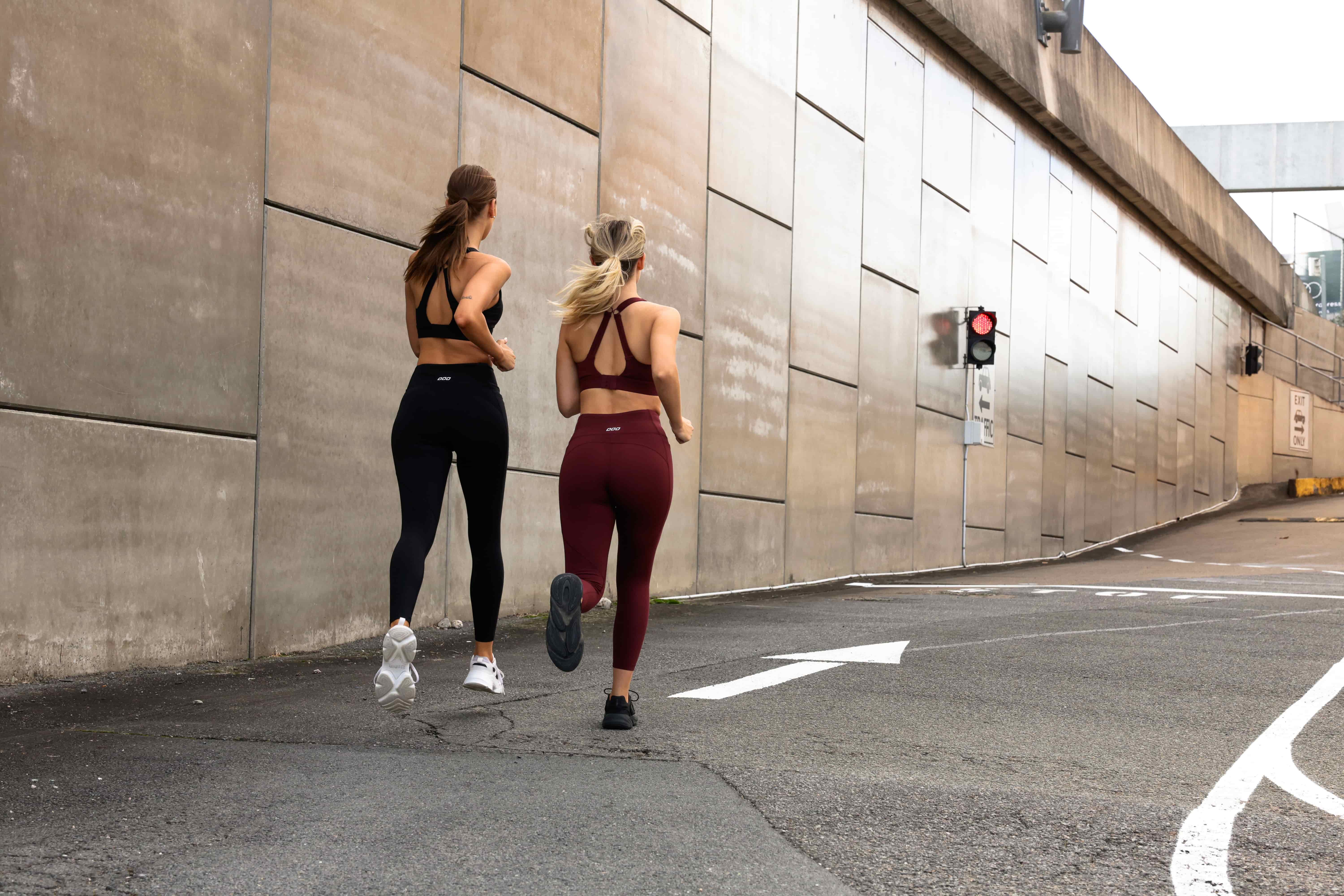 Wide Back shot of two models running wearing Amy sports bra and leggings