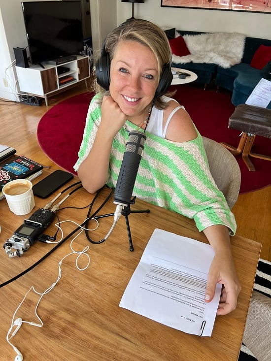 lola berry doing podcast wearing green knit and headphone sitting at table
