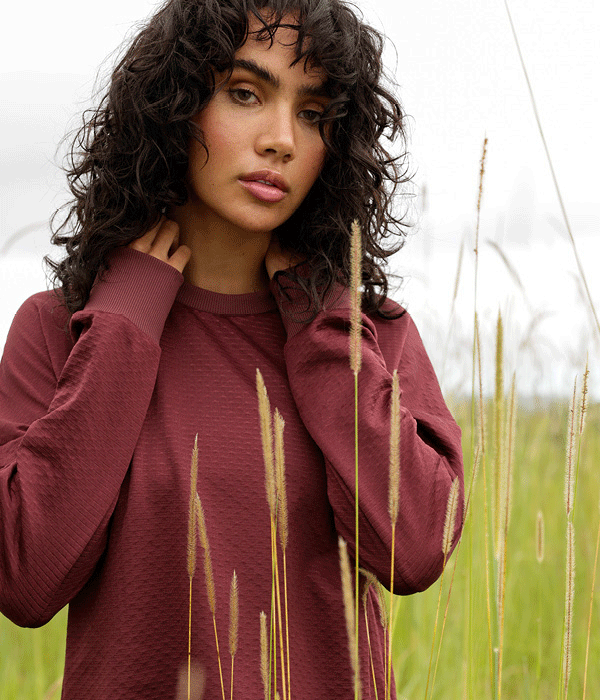 a woman wearing a burgundy red long sleeve top