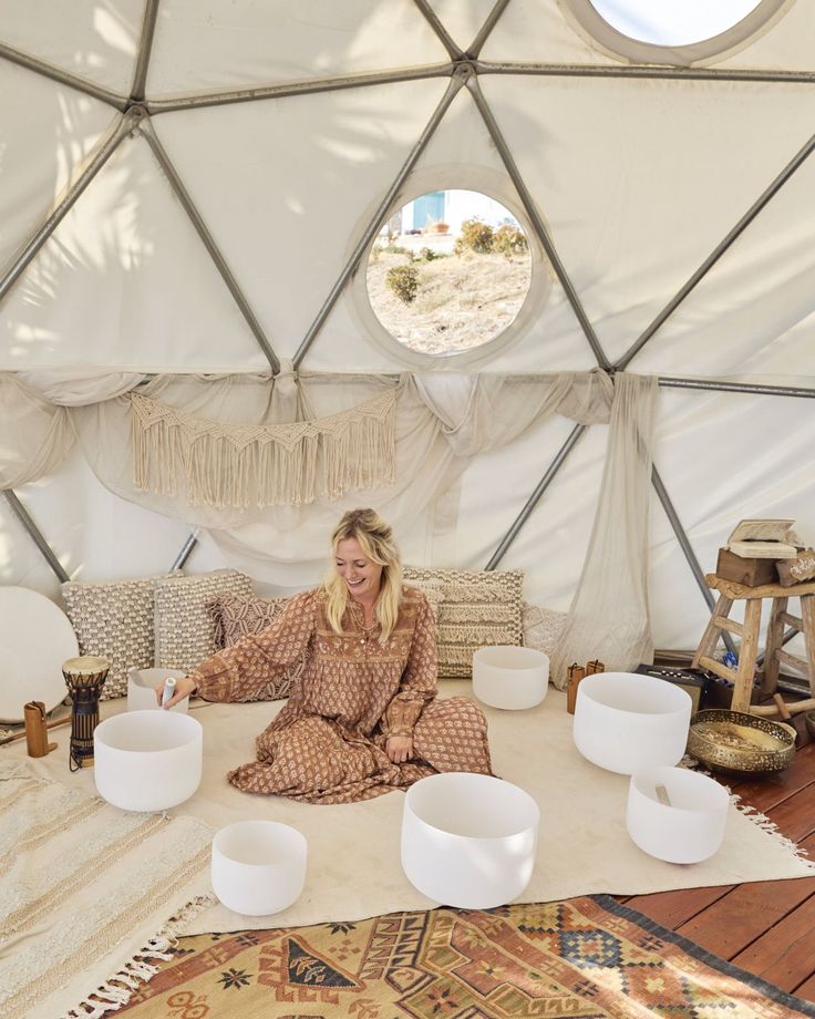 woman sitting in sound bath tent using Tibetan bowls for sound meditation