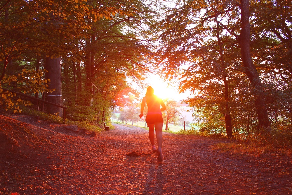 a woman running down a path in the bush at sunrise