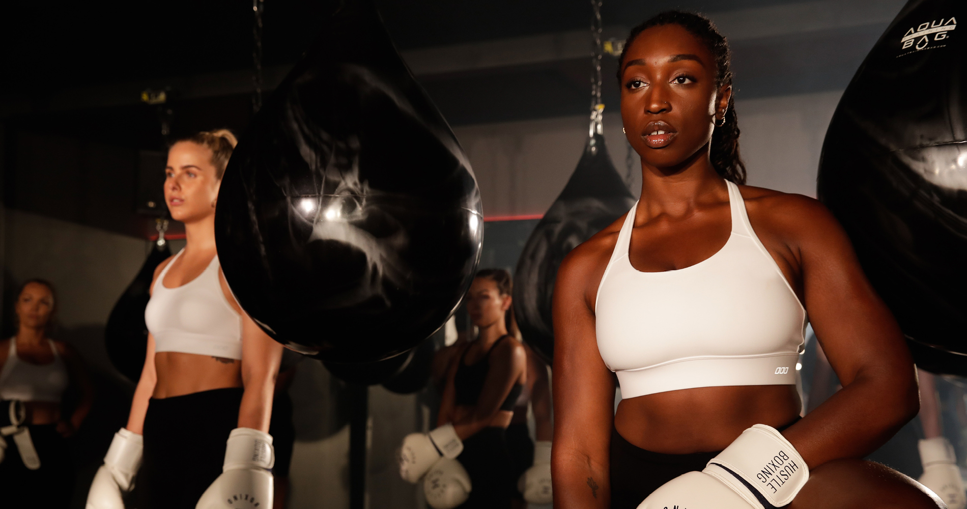 two women wearing white sports bras and boxing gloves