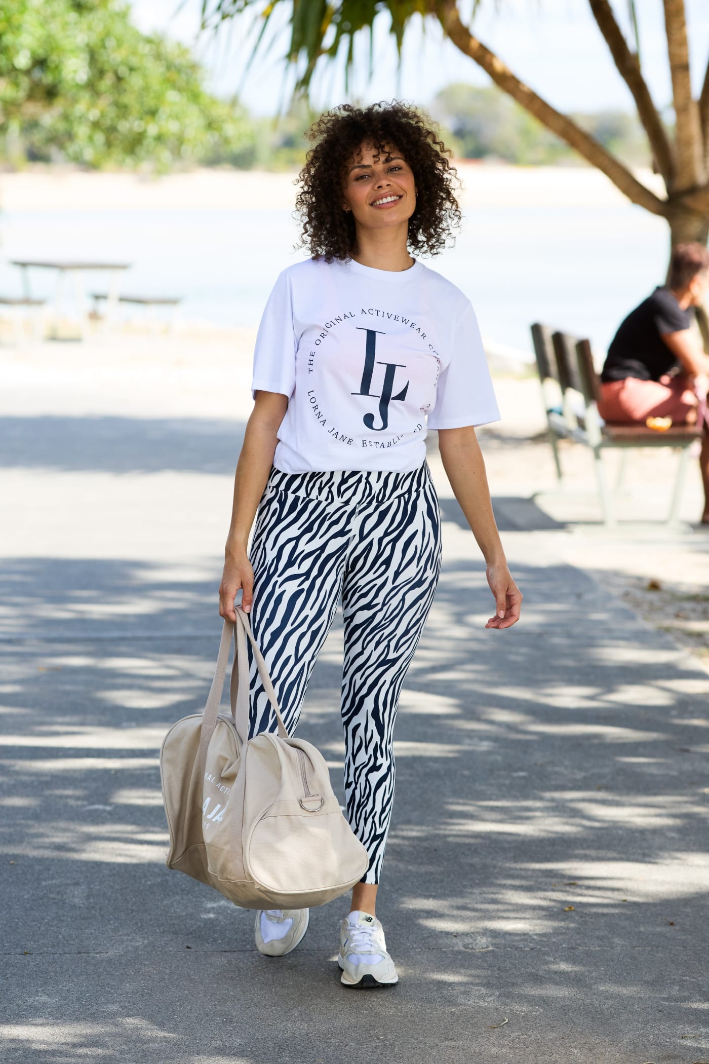 Model walking wearing a oversized tee, safari print leggings and carrying the Canvas Duffle Bag in off white