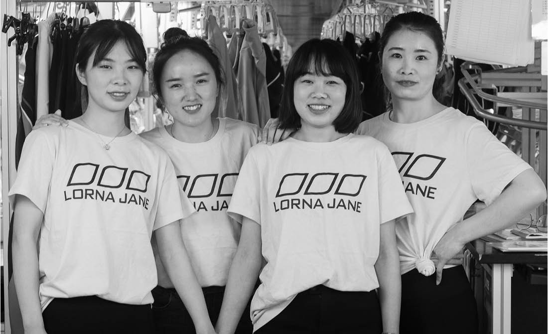 Four workers posing side by side in lorna jane t-shirts where the lorna jane garments are produced